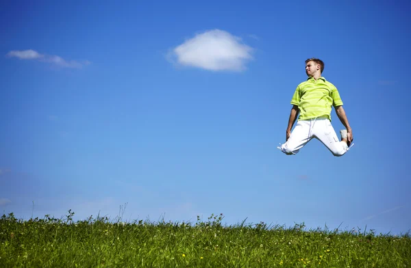 푸른 하늘에 대 한 녹색 셔츠에 있는 녀석을 점프. — 스톡 사진