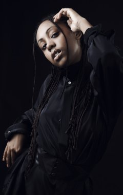 siyah arka planda poz güzel genç bir siyah kadın portresi.