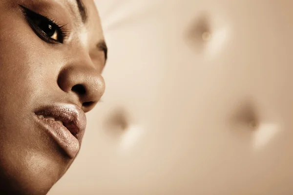 Close-up πορτρέτο του όμορφη γυναίκα αφρικανική θέτουν σε μια έκφραση μπεζ δερμάτινο σαλόνι — Φωτογραφία Αρχείου