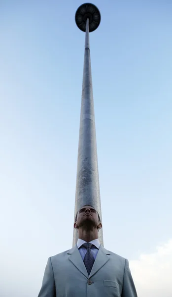 Vertikales Foto des Menschen gegen eine Säule, die in den Himmel steigt — Stockfoto