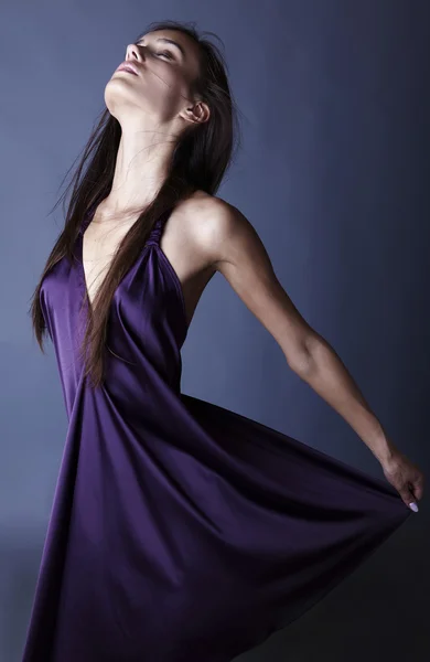 Sexy Brünette posiert im seidenen violetten Kleid. — Stockfoto