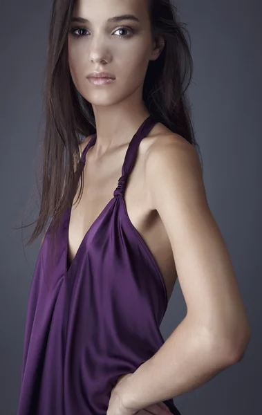 Сексуальная брюнетка позирует в шелковом фиолетовом платье . — стоковое фото