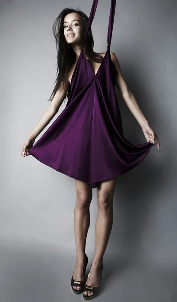 Sexig brunett poserar i violett sidenklänning. — Stockfoto