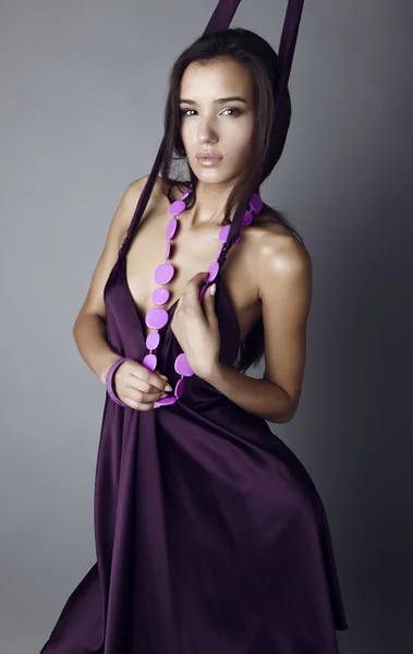 Sexig brunett poserar i violett sidenklänning. — Stockfoto
