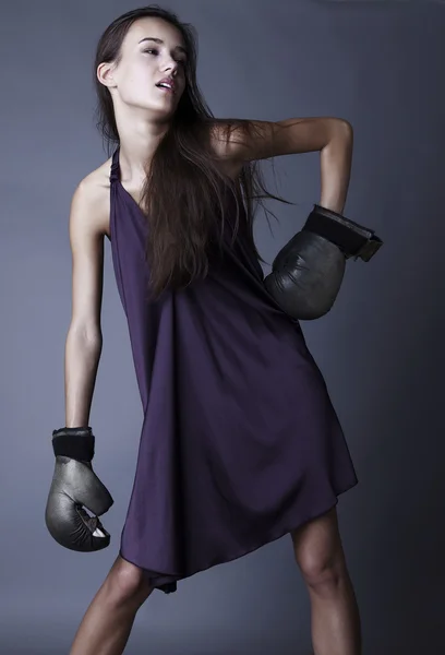 실크 바이올렛 드레스를 입고 포즈를 취하는 권투 장갑에 섹시 한 갈색 머리. — 스톡 사진