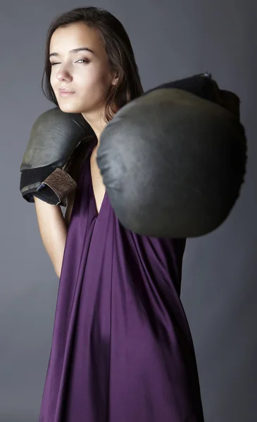 Sexig brunett i boxning handskar poserar klädd i violett sidenklänning. — Stockfoto