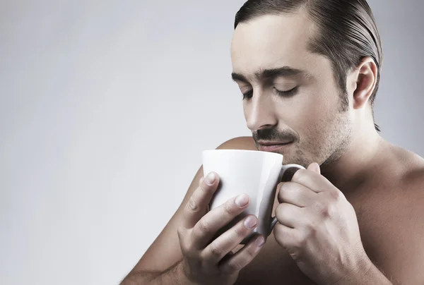 Gelukkig jonge Kaukasische kerel met een kopje koffie geïsoleerd op grijze pagina — Stockfoto