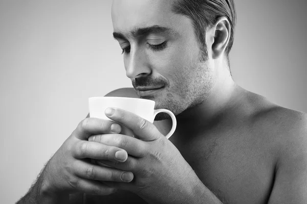 Happy young Caucasian guy having a cup of coffee isolated on gray backgroun — Stock Photo, Image