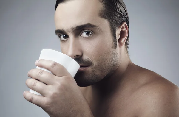 Gelukkig jonge Kaukasische kerel met een kopje koffie geïsoleerd op grijze pagina — Stockfoto