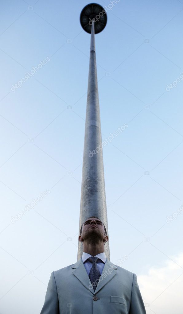Vertical photo of man against a column leaving in the sky