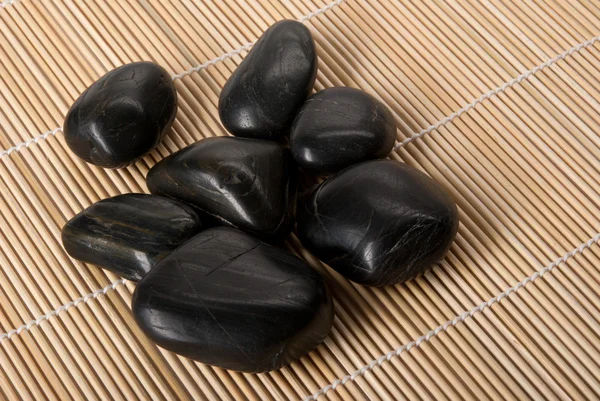 Einige dunkel glänzende Steine liegen auf Matten — Stockfoto