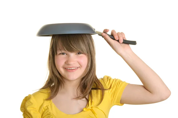 Girl holds frying pan on head and smiles — Stock Photo, Image
