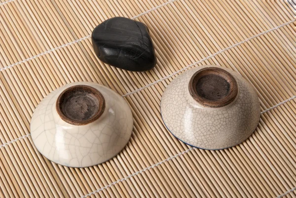 Камень и две чашки чая лежат на коврике — стоковое фото