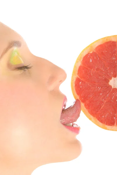 Vrouw met make-up likt grapefruit — Stockfoto