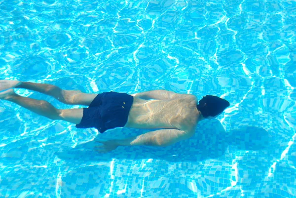 Mladý muž plavající pod vodou — Stock fotografie