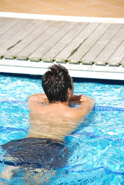 Hombre joven relajándose en el borde de la piscina — Foto de Stock