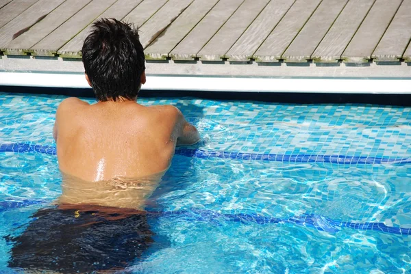 Young man relaxing at the edge of the swimming pool — Stock Photo, Image