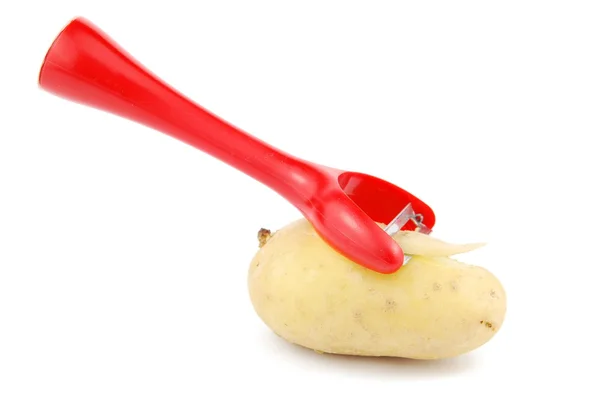 Sbucciare una patata con pelapatate su bianco — Foto Stock