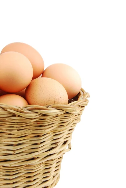 Närbild av ägg i en flätad korg på vit — Stockfoto