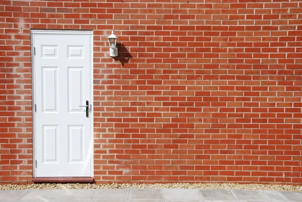 Porta branca em uma parede de tijolo — Fotografia de Stock