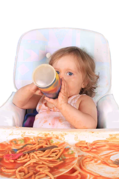 Chaotisches Baby-Mädchen trinkt Saft und isst Spaghetti — Stockfoto