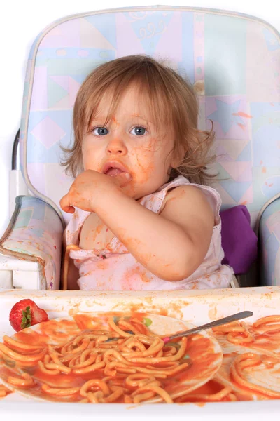 Rommelig babymeisje eten spaghetti — Stockfoto