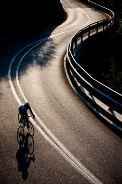 Cyclist riding along a mountain road clipart