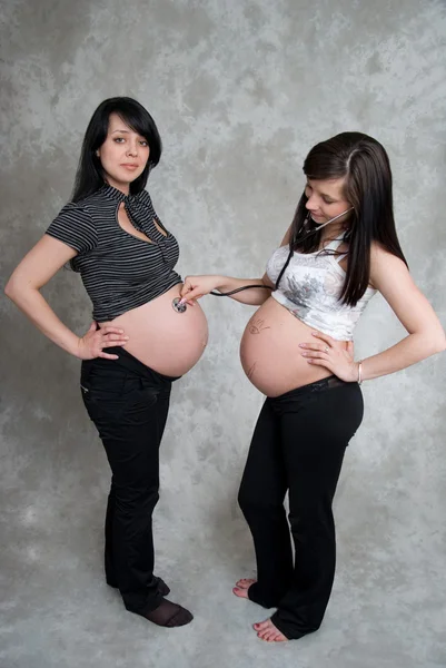 Две счастливые беременные девушки в студии — стоковое фото