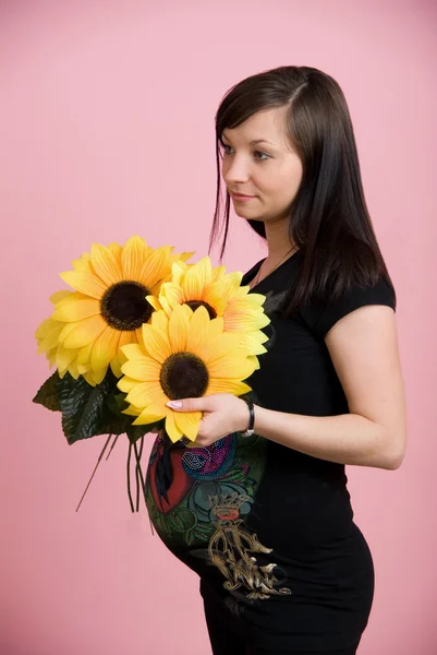 Hermosa mujer embarazada sosteniendo el vientre con flores —  Fotos de Stock