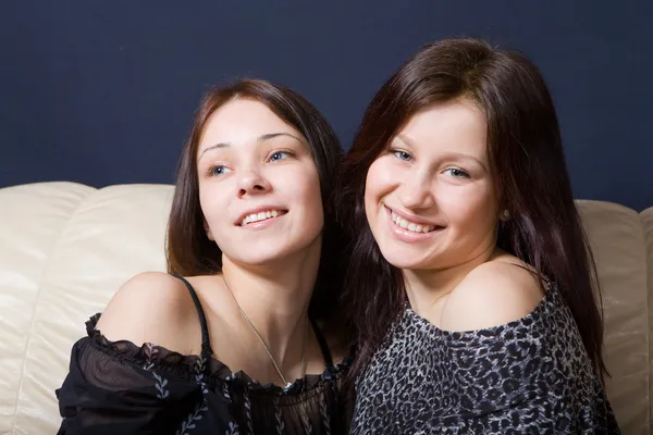 Zwei glückliche Mädchen sitzen auf einem Sofa — Stockfoto
