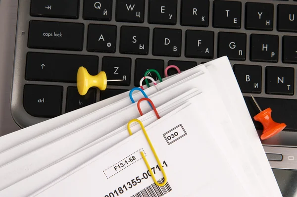 Documentos em papel com clipes no teclado do laptop — Fotografia de Stock