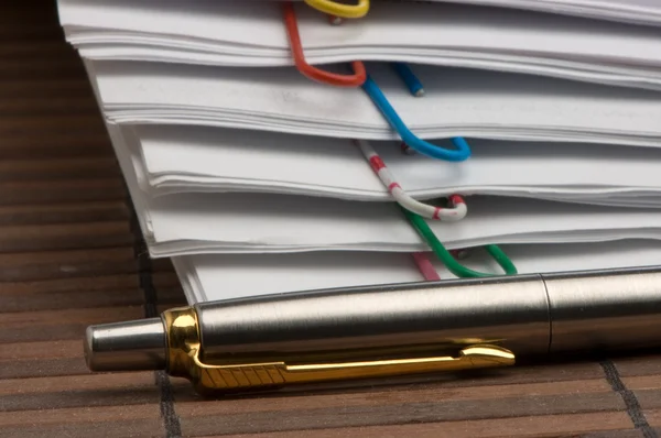 Бумажные листы с зажимами и ручкой — стоковое фото