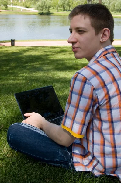 Young man using laptop in summer park — Stock Photo, Image