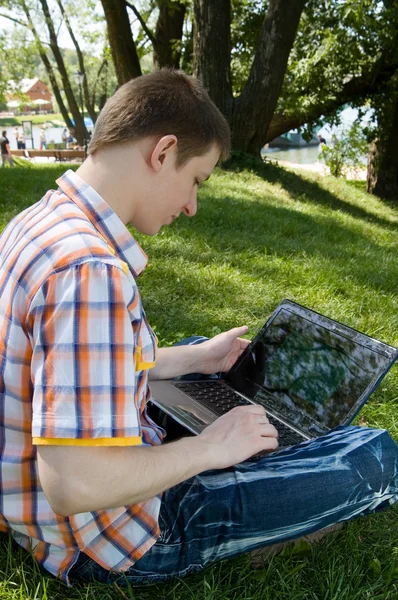 stock image Young man using laptop in summer park