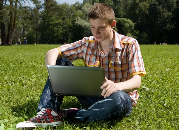 stock image Young man using laptop in summer park