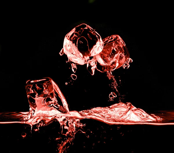 Ледяные кубики падают в воду с брызгами — стоковое фото