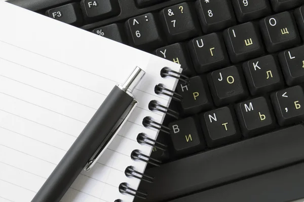 Notebook en pen op het toetsenbord — Stockfoto