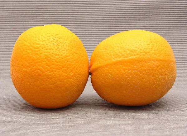 Δύο πορτοκάλια μπροστά από ένα γκρίζο φόντο — Φωτογραφία Αρχείου