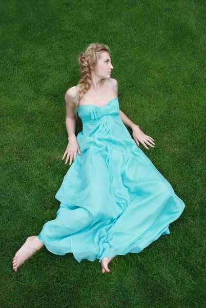 Flicka i blå klänning på det gröna gräset — Stockfoto