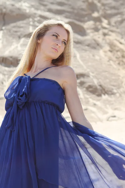 Meisje in donker blauwe jurk op het zand — Stockfoto