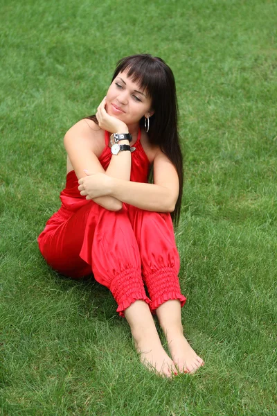 Brunetka dziewczynka w czerwonym na trawie — Zdjęcie stockowe