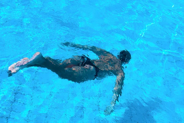 Мужчина плавает под водой в бассейне — стоковое фото