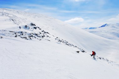 Backcountry snowboarder climbing up clipart