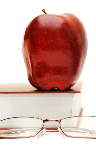 Красное яблоко и очки на книге — стоковое фото