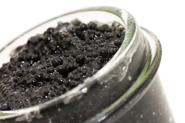 Caviar negro en un frasco de vidrio sobre un blanco — Foto de Stock