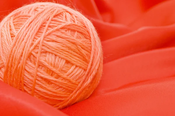 Palla di fili su un tessuto rosso — Foto Stock