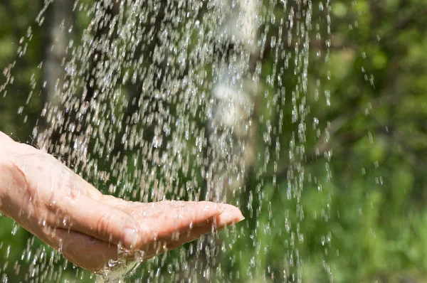 Les mains qui attrapent l'eau propre tombant de près — Photo