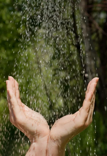 Les mains qui attrapent l'eau propre tombant de près — Photo