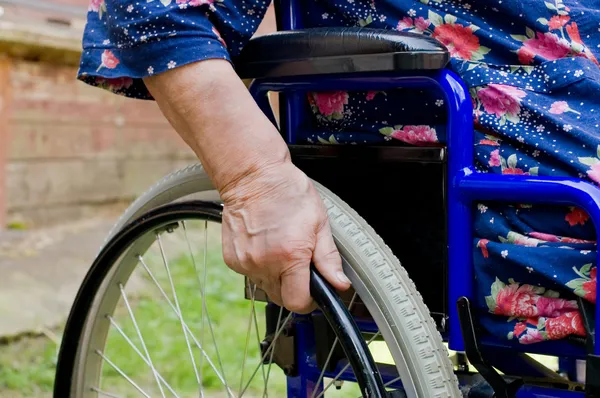Main de la vieille femme sur un fauteuil invalide — Photo