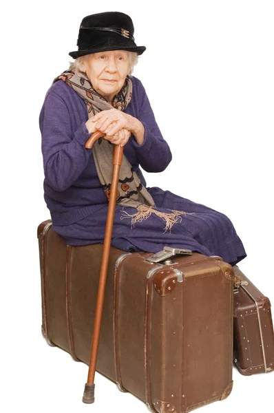 A senhora velha senta-se em uma mala — Fotografia de Stock